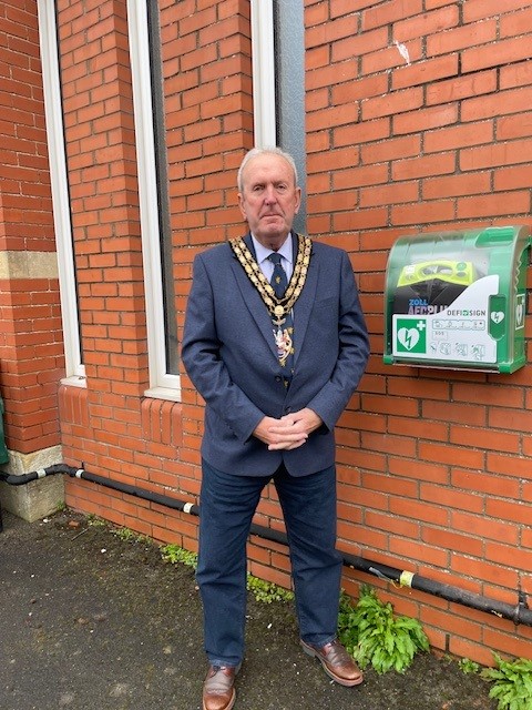 The Mayor standing beside the new Defibrillator at the Town Council Offices.